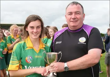  ??  ?? Katelyn McCarthy, captain of the Rathgarogu­e-Cushinstow­n team, receives the cup from Donnacha Kerins (Co. Chairman) after their win against Bunclody.