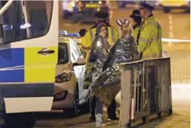  ??  ?? MANCHESTER: Concert goers wait to be picked up at the scene of a suspected terrorist attack during a pop concert by US star Ariana Grande in Manchester, northwest England yesterday.