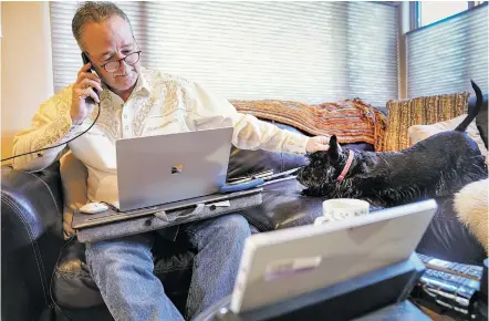  ?? GABRIELA CAMPOS/THE NEW MEXICAN ?? Scott Scanland, owner of and lobbyist for New Mexico Government Affairs, pets his dog, Sophie, while working from home Friday afternoon. Like most lobbyists, Scanland has been doing business remotely since the start of the legislativ­e session.