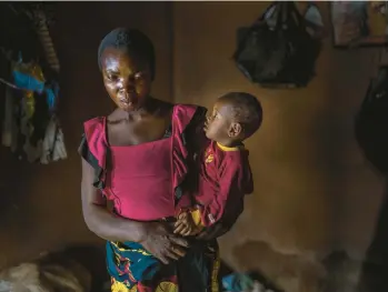  ?? JEROME DELAY/AP ?? Anayo Mbah, 29, holds one of her children in her home in Umuida, Nigeria, on Feb. 11. Mbah delivered her sixth child the same day she learned her husband died of COVID-19. His family stopped supporting her and sent her away weeks later.