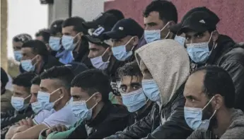  ?? JAVIER BAULUZ / AP ?? Migrants from Morocco sit after arriving at the coast of the Canary Islands, having made the perilous crossing of the Atlantic Ocean by sailing on a wooden boat. Spain’s government is scrambling to manage the steady stream of migrants to its Canary Islands from West Africa.