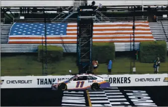  ?? PHOTOS: MATT SLOCUM — THE ASSOCIATED PRESS ?? Denny Hamlin takes the checkered flag as he crosses the finish line to win the NASCAR Cup race at Pocono.