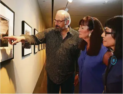  ?? Jerry Baker ?? Photograph­er Mark Burns, left, talks about his 2015 photo of Olympic National Park in Washington with Pearl Fincher Museum of Fine Arts curator Terry Capps and Lone Star College-Kingwood Professor of Art Mari Omori.