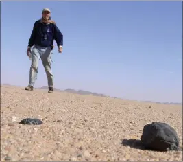  ?? COURTESY OF SETI INSTITUTE/NASA AMES RESEARCH CENTER ?? Meteor astronomer Peter Jenniskens, with the SETI Institute and NASA Ames Research Center, stands near two meteorites from asteroid 2008Tc3in the Nubian Desert of Sudan.