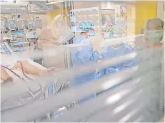  ?? Photo — AFP ?? Health workers attend to a Covid-19 patient at the intensive care unit of the Vall d’Hebron hospital in Barcelona. Spain’s death toll surged over 9,000 as infections passed the 100,000 mark, but the rate of new cases continued to slow, suggesting the epidemic may be peaking, health chiefs said.