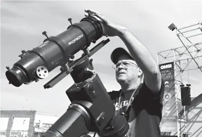  ?? Associated Press ?? n Ray Cooper, volunteer for the Oregon Museum of Science and Industry, preps his equipment Sunday to provide live video of today’s solar eclipse at the state fairground­s in Salem, Ore.