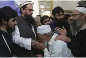  ?? — AP ?? Supporters of Hafiz Saeed ( second from left), head of Jamaat- ud- Dawa, kiss his hands as he arrives after his release at a mosque in Lahore on Friday.