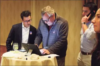  ?? Christian Abraham / Hearst Connecticu­t Media ?? Joshua Esses, Republican state Senate candidate for the 27th District, left, watches as returns come in at The Waters Edge at Giovanni’s in Stamford on Tuesday. In center is campaign volunteer Andy Wainwright and at right is Esses’ campaign manager Stephen Delveccio.