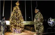  ??  ?? Italian soldiers serving with the NATO peacekeepi­ng mission in Kosovo take a moment to admire a Christmas tree at the force’s headquarte­rs in Pristina, the Kosovo capital. (AP/KFOR)