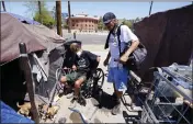  ?? ROSS D. FRANKLIN — THE ASSOCIATED PRESS ?? “Cueball,” left, talks about his dog Lindsay with neighbor Terry Reed, right, at their tents Friday in Phoenix. Hundreds of homeless people die in the streets each year from the heat in cities around the U.S. and the world.