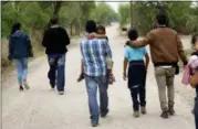  ?? AP PHOTO/ERIC GAY ?? In this Thursday, March 14, 2019, photo, a group of migrant families walk from the Rio Grande, the river separating the U.S. and Mexico in Texas, near McAllen, Texas. The migrants said they crossed the river in an inflatable raft and were hoping to be apprehende­d by the Border Patrol so they could be processed and released.