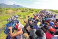  ?? REBECCA BLACKWELL/ASSOCIATED PRESS ?? A man holds up a stroller as hundreds of migrants hitch a ride on the back of a truck in Mexico on Tuesday. Organizers are negotiatin­g for bus transporta­tion.