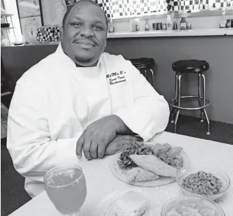  ??  ?? Keith Patterson poses for a photo with fried catfish, collard greens, yams, black-eyed peas, cornbread, peach cobbler and Kool-Aid in 2009 at his MaMa E's restaurant in Oklahoma City. [THE OKLAHOMAN ARCHIVES]