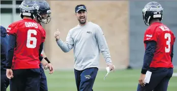  ?? ELAINE THOMPSON/THE ASSOCIATED PRESS ?? New Seahawks offensive co-ordinator Brian Schottenhe­imer works with quarterbac­ks Austin Davis, Alex McGough and Russell Wilson during practice on Thursday.