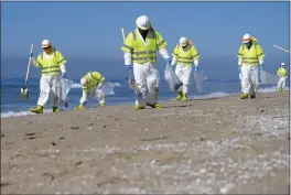  ?? PHOTOS BY RINGO H.W. CHIU — THE ASSOCIATED PRESS ?? Workers in protective suits clean the contaminat­ed beach in Huntington Beach, on Tuesday after an oil spill.