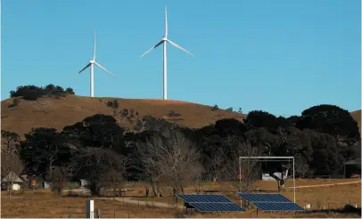  ?? BLOOMBERG PHOTO ?? Solar panels stand in a field in front of wind turbines. B.C.’s greenhouse gas emissions are near 2007 levels, despite policies meant to reduce emissions.