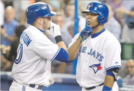  ?? FRED THORNHILL/THE CANADIAN PRESS ?? Blue Jays first baseman Edwin Encarnacio­n, right, greets teammate Josh Donaldson with a whisper gesture after Donaldson pounded a home run against the Minnesota Twins in Toronto on Tuesday. The Blue Jays downed the Twins 3-1, Toronto’s third win in a...