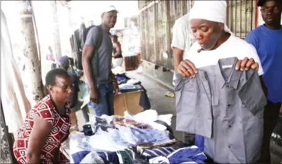  ?? — Picture by Munyaradzi Chamalimba ?? Chipo Pinduka (right) displays some of the school uniforms on sale along Leopold Takawira Street yesterday. The third term begins tomorrow and most parents will be making their last-minute shopping for various accessorie­s.