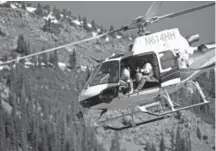  ??  ?? Colorado Department of Transporta­tion avalanche mitigation experts prepare to drop bombs from a helicopter to release any unstable snow above the winding, high-altitude highway between Leadville and Aspen.