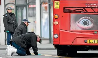  ?? AP ?? Police officers look under a bus as they work at the scene of Monday’s terror stabbing attack in the Streatham area of south London.