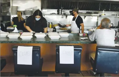  ?? PHOTOS BY CHRIS RILEY — TIMES-HERALD ?? A lone diner sits at the counter at Scotty’s Restaurant as workers prepare orders for pick-up. Some counter seats and tables were closed to promote social distancing as the restaurant reopened for dine-in customers on Friday.