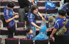  ?? — AP ?? Clean sweep: Japan fans collect trash after their match against Spain at the Khalifa Internatio­nal Stadium.