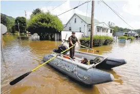  ?? STEVE HELBER/ASSOCIATED PRESS ?? Lt. Dennis Feazell, of the West Virginia Department of Natural Resources, rows his boat Saturday as he and a co-worker search flooded homes in Rainelle, West Virginia.