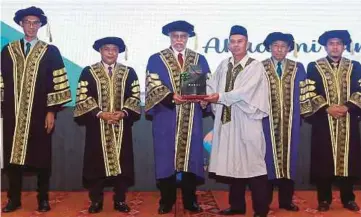  ?? ?? ZAINAL Abidin (tiga dari kiri) memberikan sijil graduasi kepada Rodzlan yang mewakili arwah anak lelakinya, Mohammad Fadzilah yang meninggal dunia akibat ketumbuhan otak pada Majlis Graduasi dan Apresiasi Asnaf Latihan dan Kemahiran Industri MAIWP.