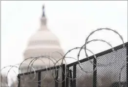  ?? MANUEL BALCE CENETA AP ?? Razor wire and fencing surround the U.S. Capitol weeks after the Jan. 6 breach. One congressma­n likened it to working inside a minimum-security prision.