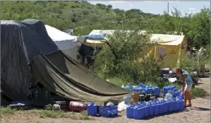  ?? AP PHOTO/AMANDA LEE MYERS ?? In this Aug. 5, 2010, file photo, No More Deaths volunteer Katie Maloney checks water jugs at the group’s camp before heading out to supply water stations for illegal immigrants near Arivaca, Ariz., about 13 miles north of Mexico.