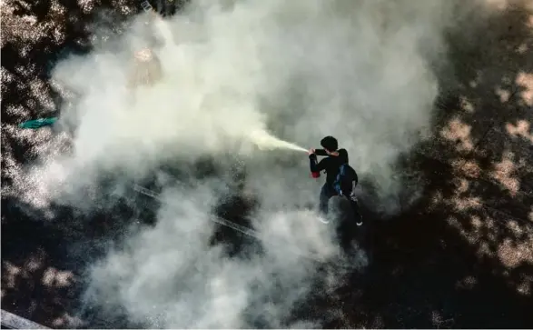  ?? Photo Sai Aung Main. AFP ?? A Rangoun, dimanche, un manifestan­t utilise un extincteur pour résister à la police.