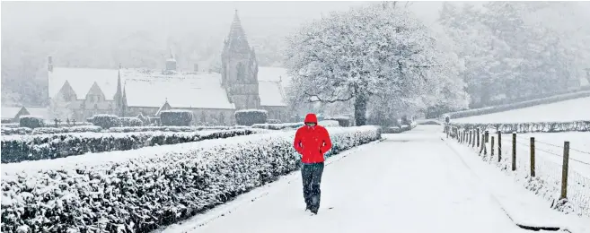  ??  ?? A walker endures more heavy snowfall yesterday on a lane by the Pantasaph Franciscan Friary in Flintshire, northeast Wales. A yellow weather warning had been put in place