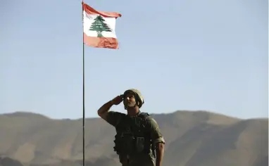  ?? PICTURE: AP ?? LIBERATED: A Lebanese army soldier salutes the national flag on the outskirts of Ras Baalbek, north-east Lebanon. Islamic State militants left the border area with Syria on Monday as part of a negotiated deal to end the extremist group’s presence there.