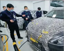  ?? LI XIN / XINHUA ?? Technical staff members at the R& D center of Beijing Electric Vehicle Co, a subsidiary of Beijing Automotive Group Co, conduct a charging test on a new energy vehicle on April 3.