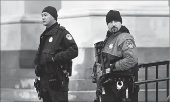  ?? EVELYN HOCKSTEIN / REUTERS ?? Police officers keep watch on the US Capitol in Washington on Wednesday. The United States is more deeply divided than ever a year after the deadly attack on Jan 6, 2021.