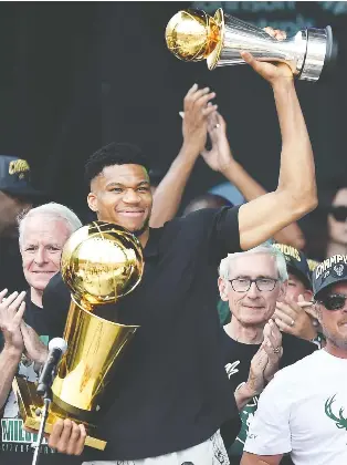  ?? PATRICK MCDERMOTT/GETTY IMAGES ?? Giannis Antetokoun­mpo hoists his post-season hardware during the Bucks' victory rally Thursday at Fiserv Forum in Milwaukee, Wis., where more than 80,000 fans engaged in revelry.