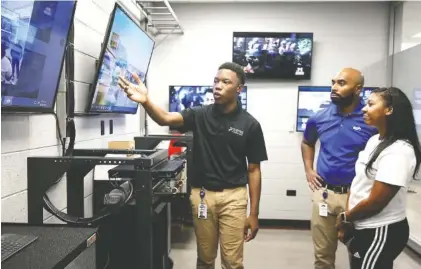  ?? STAFF PHOTOS BY ERIN O. SMITH ?? Jaylan Sims, a Tyner student, describes on Tuesday the capabiliti­es students will have in the new technology room to Jeriel Allison, a business continuity executive at EPB, and Renata Allison at Tyner Academy.