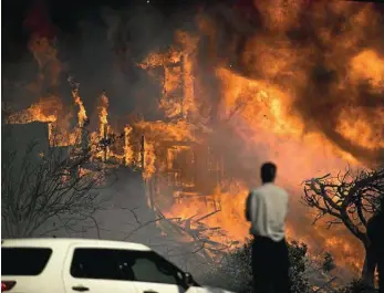  ?? PHOTO: NOAH BERGER/AP ?? HELPLESS: A bystander, possibly the home’s owner, can only watch as the building is consumed by wildfire in Ventura, California.