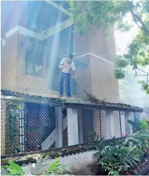  ??  ?? Leaves are cleaned out from the gutters of Summit flats in a Colombo. Pix by Indika Handuwala