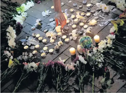  ?? Win McNamee ?? > A man tends a candle at a vigil for the woman who died and those who were injured when a car plowed into a crowd of anti-fascist counter-demonstrat­ors near a shopping area in Charlottes­ville, Virginia, USA