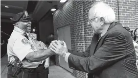  ?? THE ASSOCIATED PRESS ?? Sen. Bernie Sanders, I-Vt., right, greets a police officer during a walk around downtown in Philadelph­ia on Thursday during the final day of the Democratic National Convention.