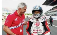  ??  ?? Well done: Former world champion Mick Doohan gives Danial Syahmi Ahmad Shahril a pat for finishing third in the Idemitsu Asia Talent Cup race in Motegi.