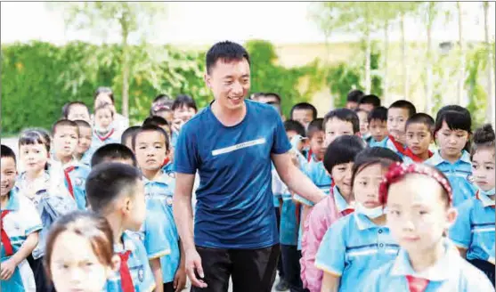  ?? PHOTO BY CHEN ZEBING / CHINA DAILY ?? Zhang Jun, a migrant from Minning town who joined the Minning Town Central Primary School as a physical education teacher, with schoolchil­dren on June 12.