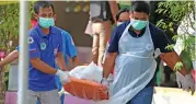 ?? (AFP) ?? Paramedics remove a body after four civil defence volunteers were shot and killed outside of a school in Pattani on Thursday
