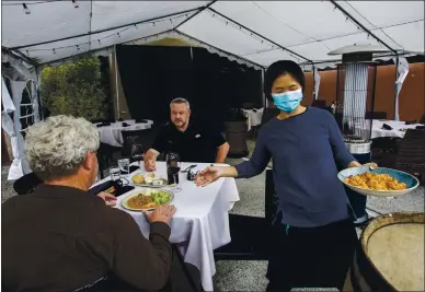  ?? KARL MONDON — STAFF PHOTOGRAPH­ER ?? Montana Jariyatamm­akaon serves Dave Edgar, left, and Chris Branan outdoors under a tent at Siena Bistro in San Jose on Wednesday.