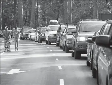  ?? Los Angeles Times/TNS/BRIAN VANDER BRUG ?? Visitors to Yosemite National Park walk in an empty bus lane while vehicles sit at a standstill on the Yosemite Valley floor last month.