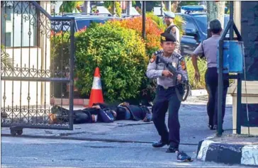  ?? WAHYUDI/AFP ?? Indonesian policemen secure the site outside the police headquarte­r in Pekanbaru, Riau, following attacks on Wednesday.