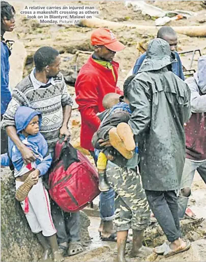  ?? Picture: AP ?? A relative carries an injured man cross a makeshift crossing as others look on in Blantyre, Malawi on Monday.