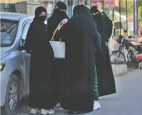  ?? AHMAD SAHEL ARMAN/AFP ?? Women wearing niqab garments stand along a street in Kabul on Saturday, the day the Taliban imposed some of the harshest restrictio­ns on Afghanista­n's women since they seized power last fall. Under the new rules, women must fully cover in public, ideally with the traditiona­l burqa.