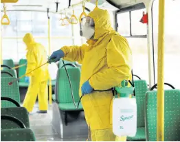  ??  ?? Employees wearing protective gear spray disinfecta­nt to sanitise a passenger bus as a preventive measure against the coronaviru­s in Lviv, Ukraine, yesterday.